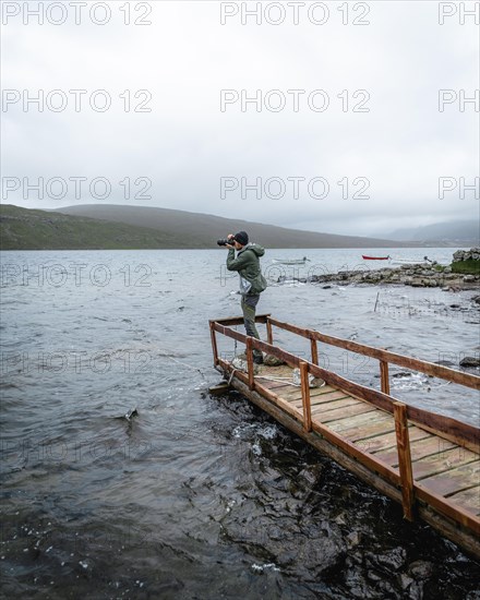 Hiker photographed on a wooden footbridge above Lake Leitisvatn