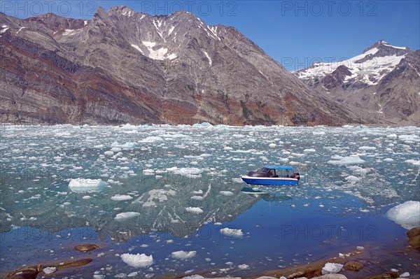 View of a blue small boat and a fjord filled with drift ice