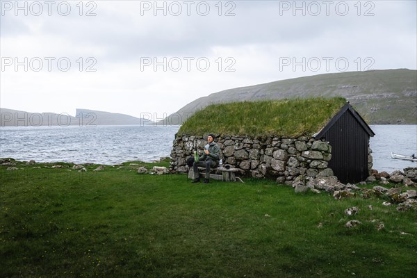 Hiker eating biscuits on a bench in front of a stone hut