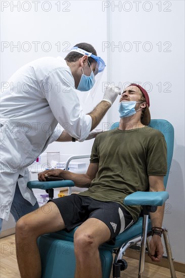 Doctor in protective clothing does an antigen test on a young man