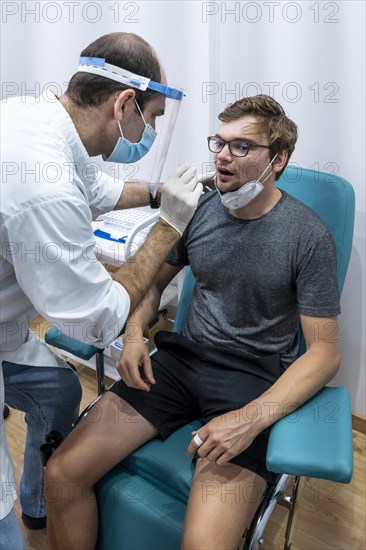 Doctor in protective clothing does an antigen test on a young man