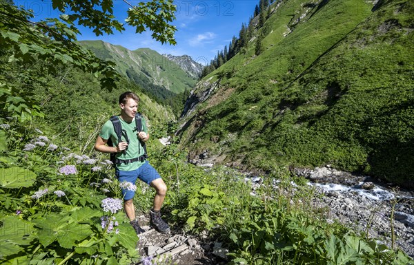 Hiker between flowers at a stream