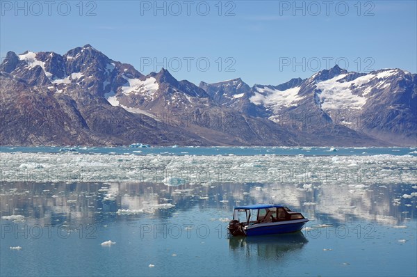 View of a blue small boat and a fjord filled with drift ice