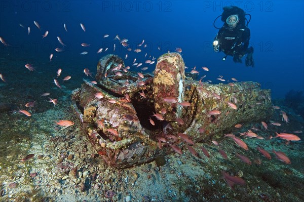 Diver looks at car wreck under water