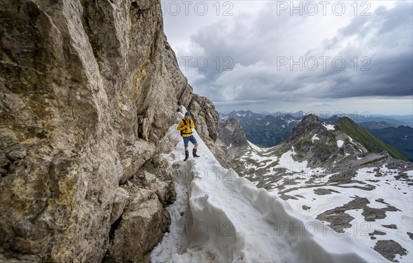 Hikers on snow remnants in rocky terrain