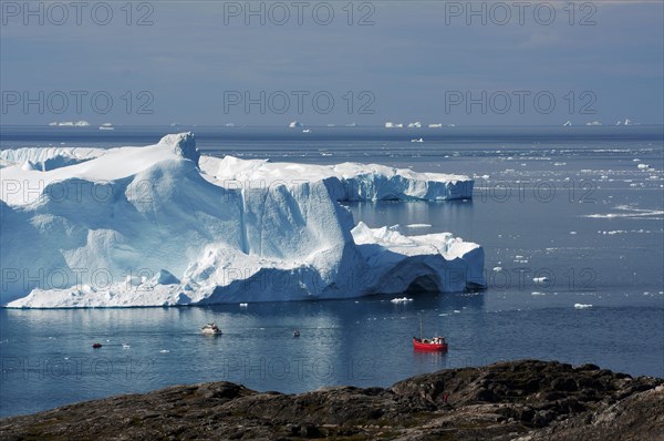 View of small fishing boat and bay with icebergs