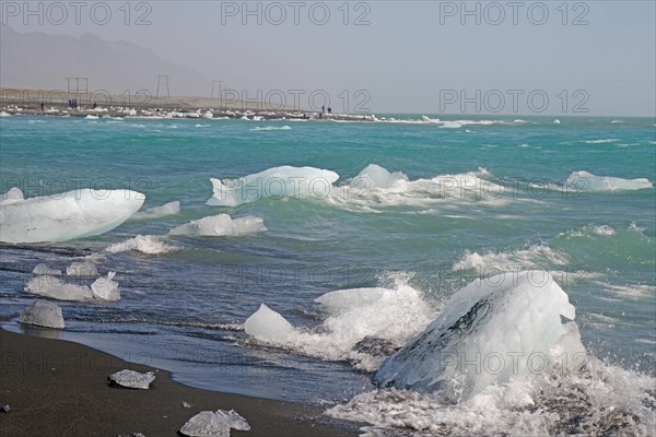 Piece of ice on black sand beach and in the river