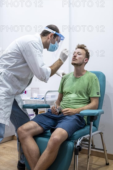 Doctor in protective clothing does an antigen test on a young man