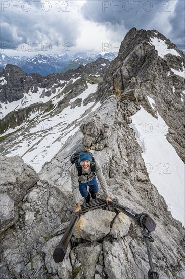 Hiker climbing metal ladder on rock