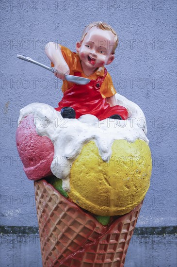 Advertising figure in front of an ice cream parlor: small child sitting in an ice cream cone