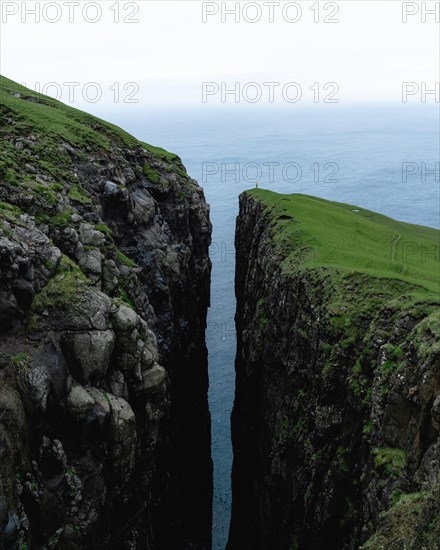 Small person standing on cliff with deep crevice