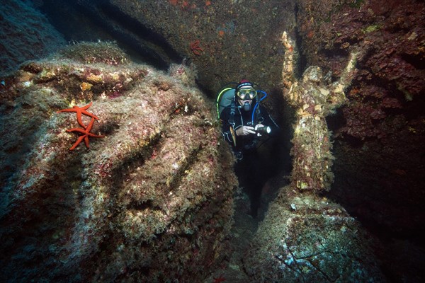 Diver looking at and illuminating statue of Christ with raised arms