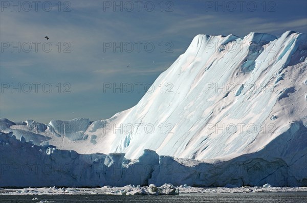 Small fishing boat in front of huge icebergs and drift ice