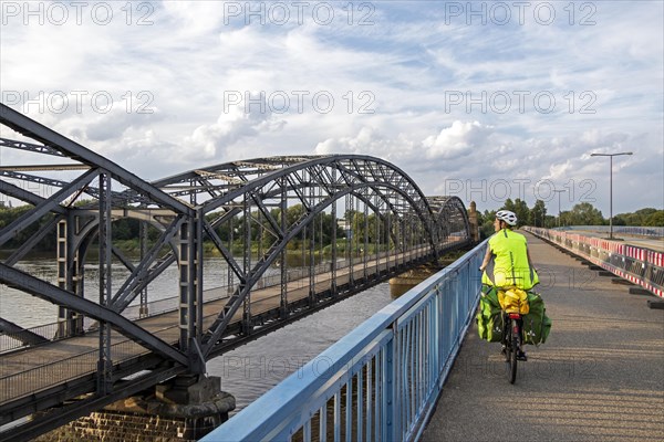 Woman riding her bicycle over bridge next to the Alte Harbruecker Elbbruecke