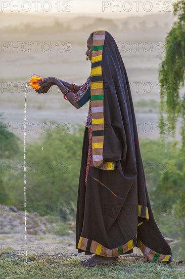 Ahir woman in traditional colorful cloth pouring water