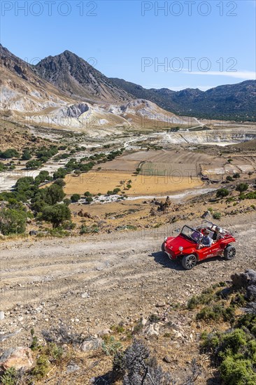 Tourists explore Nysiros with a red car on a gravel road
