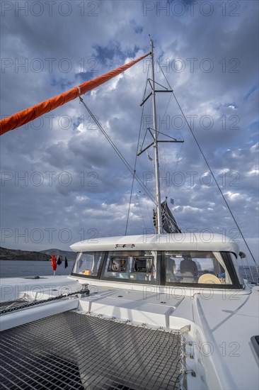 Recessed headsail and deck with net of a sailing catamaran in evening light