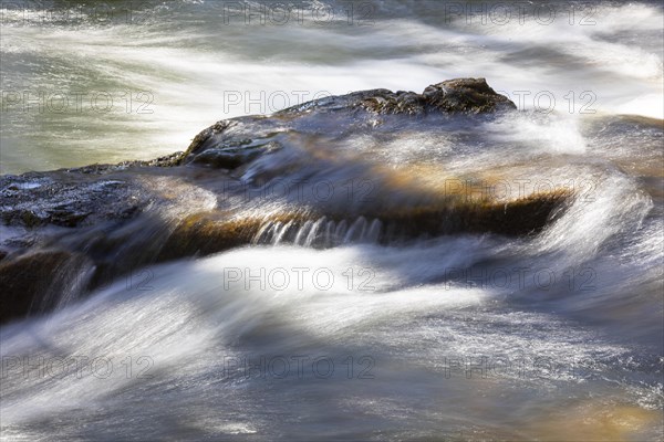 Flowing water in a rocky stream bed with light reflections
