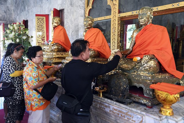 Believers paste statues of monks with gold leaf