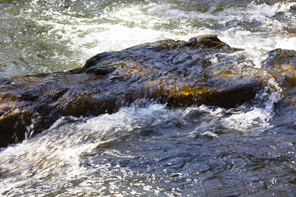 Flowing water in a rocky stream bed with light reflections