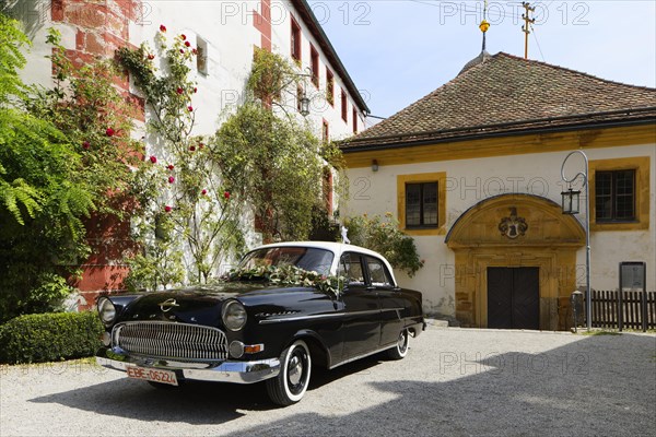 Church on the right and forecourt with vintage Opel Kapitaen