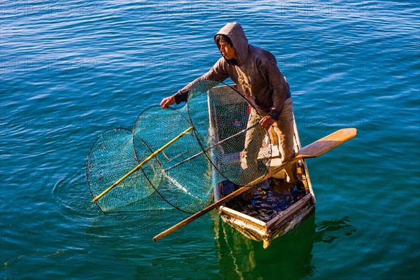 Fisherman with fish trap in his floating coffin