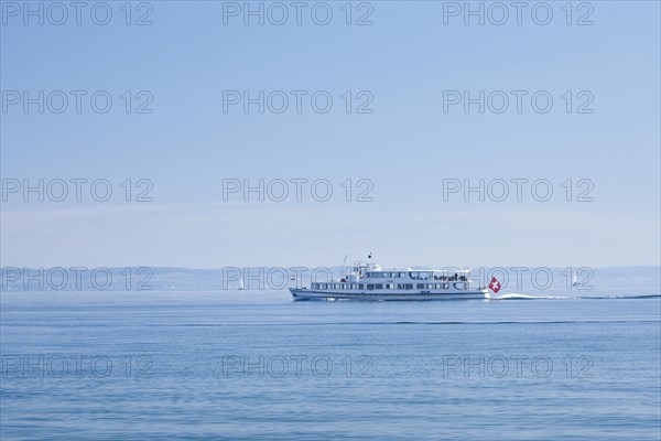 View from Arbon over the shimmering blue Lake Constance with a scheduled boat in sunny weather and blue sky in summer