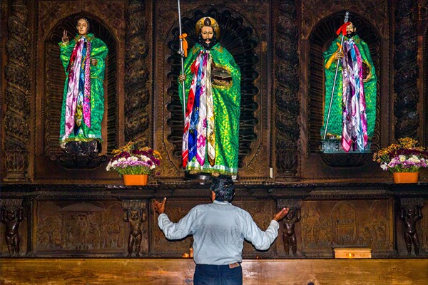 Shaman talking to wooden figures of the saints