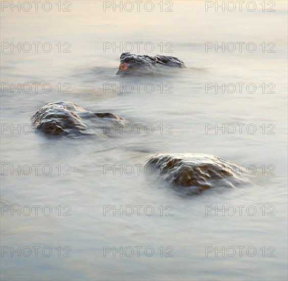 Light play and stones in the water at sunrise photographed with slow shutter speed