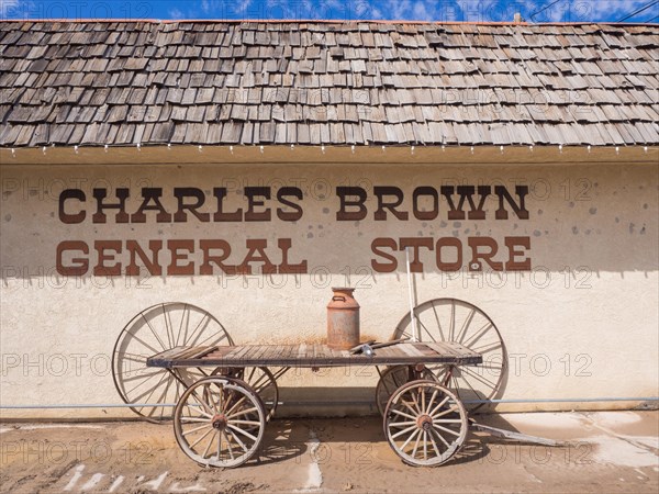 Old cart with rusty milk can in front of General Store