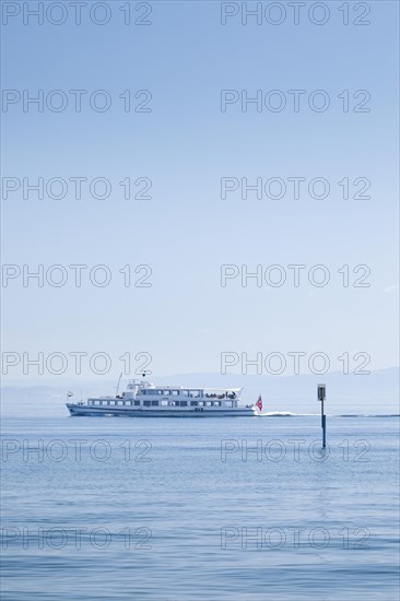 View from Arbon over the shimmering blue Lake Constance with a scheduled boat in sunny weather and blue sky in summer