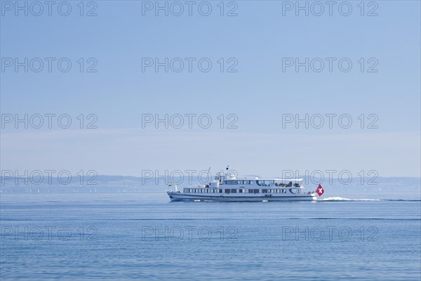 View from Arbon over the shimmering blue Lake Constance with a scheduled boat in sunny weather and blue sky in summer