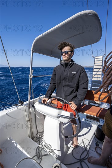 Man at the wheel in the cockpit on the deck of a sailing catamaran