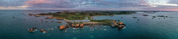 Panorama drone shot from the Atlantic Ocean onto the granite coast of Plougrescant with a view of the house between the rocks (Le gouffre de Plougrescant) at sunset