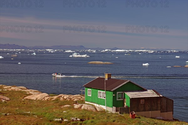 Simple dwelling house on the edge of an iceberg-covered bay