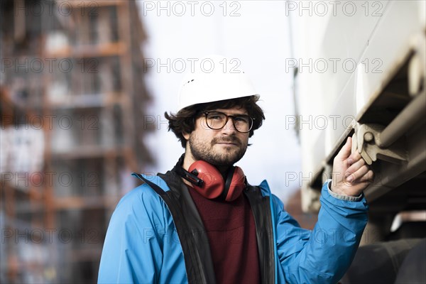 Young engineer wearing a helmet and hearing protection at a work site outside on a construction site