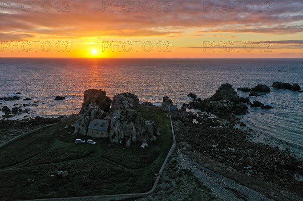 Drone shot from the mainland of the house between the rocks (Le gouffre de Plougrescant) and the Atlantic Ocean at sunset