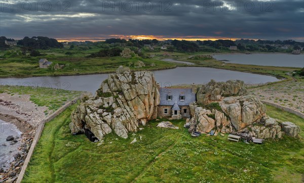 Drone shot from the Atlantic Ocean onto the house between the rocks (Le gouffre de Plougrescant) at sunset