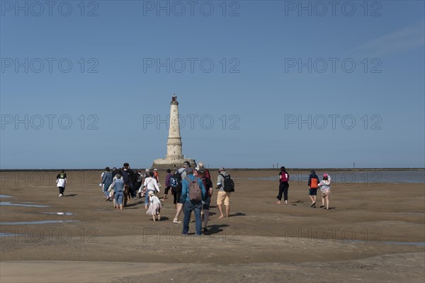 Tourists walk to Cordouan lighthouse at low tide