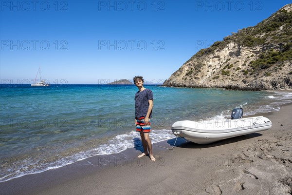 Young man with dinghy on a beach in Gyali