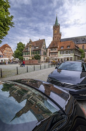 The market square with St. Mary's column at the fountain and the tower of the Catholic Church of junglefowl (Gallus) reflected on the bonnet of a car