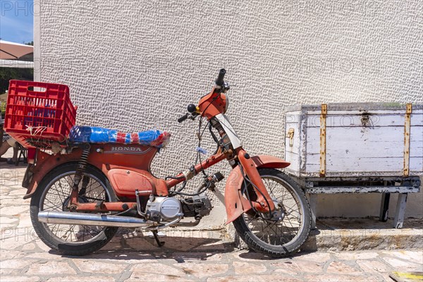 Old red scooter in front of a wall