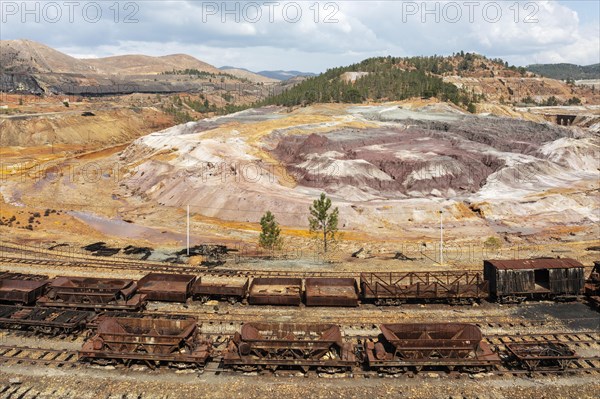 Disused wagons at the dramatically scarred landscape of mineral-rich ground and rock at the Rio Tinto mines