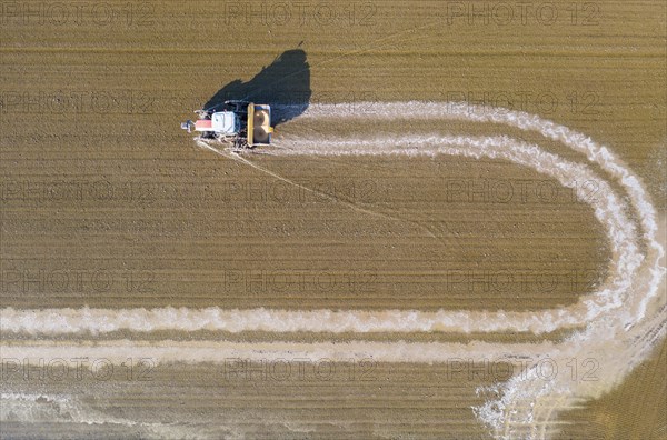 Tractor sowing rice seeds in a flooded rice field in May