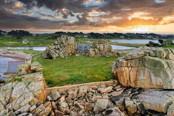 Drone shot from the Atlantic Ocean onto the granite coast of Plougrescant with a view of the house between the rocks (Le gouffre de Plougrescant) at sunset