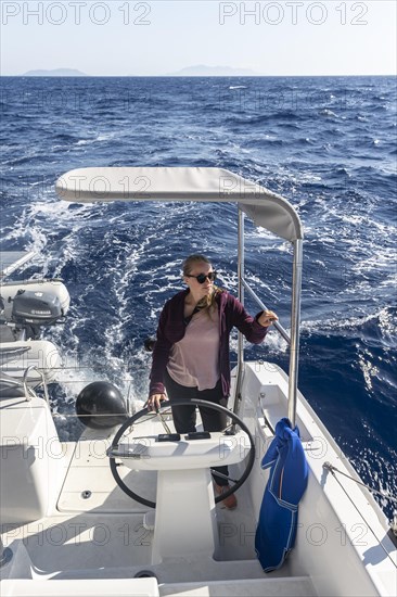 Young woman at the wheel in the cockpit on the deck of a sailing catamaran