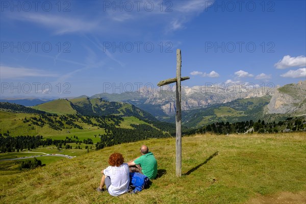 Hikers sitting at the summit cross at the Sella Pass