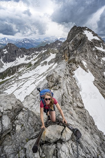 Hiker climbing metal ladder on rock