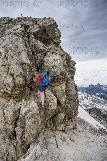 Hiker climbs metal ladder on rock