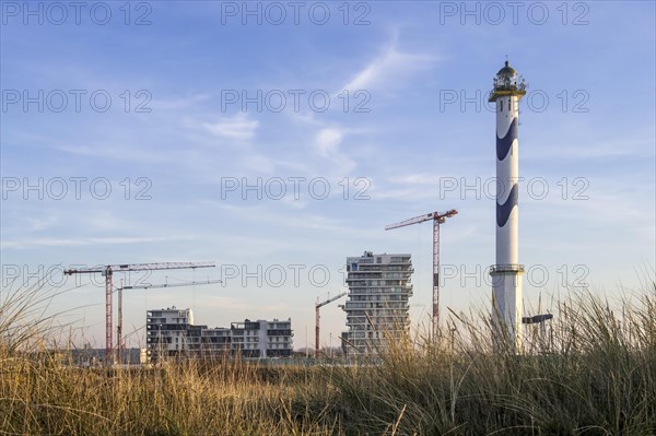 Lange Nelle lighthouse and new flats under construction for the Oosteroever real estate project in the port of Ostend on the Belgian North Sea coast